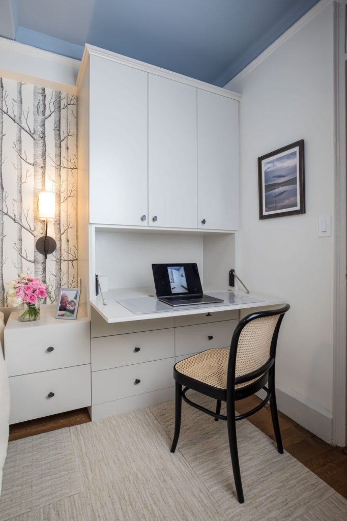 Creating a space plan: white bedroom cabinets open to desk, with forest wallpaper, pink flowers and caned chair.