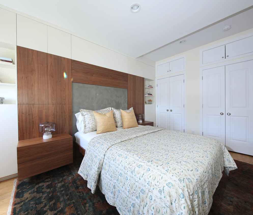 Negotiating: Hiring for Your Design Project: Modern bedroom featuring the finished custom walnut and plywood headboard and nightstands, with white walls, cabinetry and dark, patterned rug.