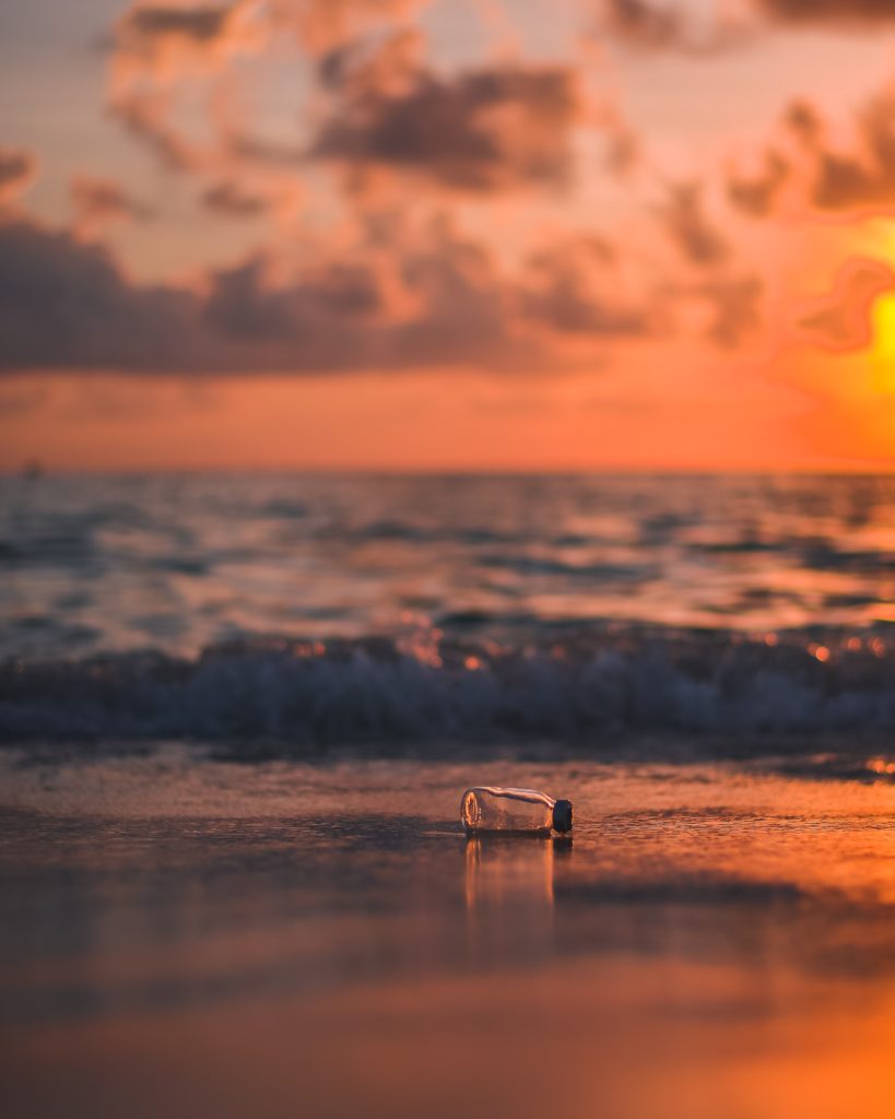 Plastic bottle litter on a beach at sunset.