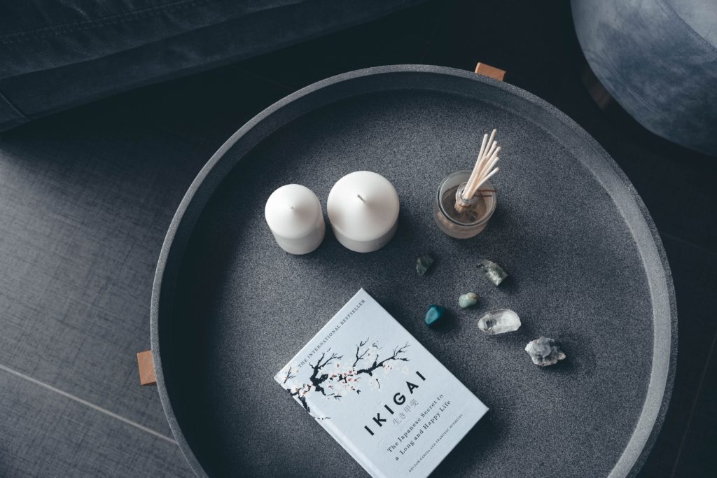 Project mindset: Grey end table with candles, incense, stones and book, viewed from above in grey living room.
