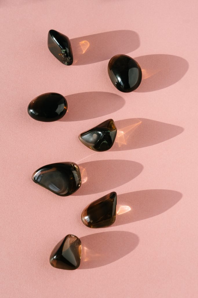 Project mindset: polished clear, brown stones on pink surface with sunlight from the left.