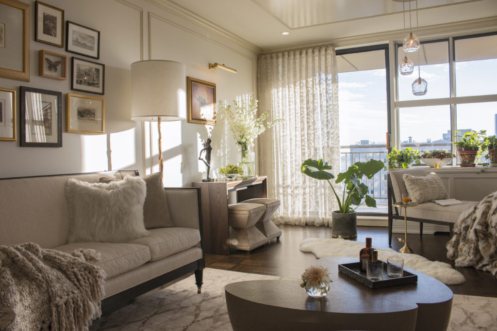 Working with a designer: living room with neutral tones, sofa, day bed, solid wood coffee table, gold and white light fixtures, and view of Manhattan.