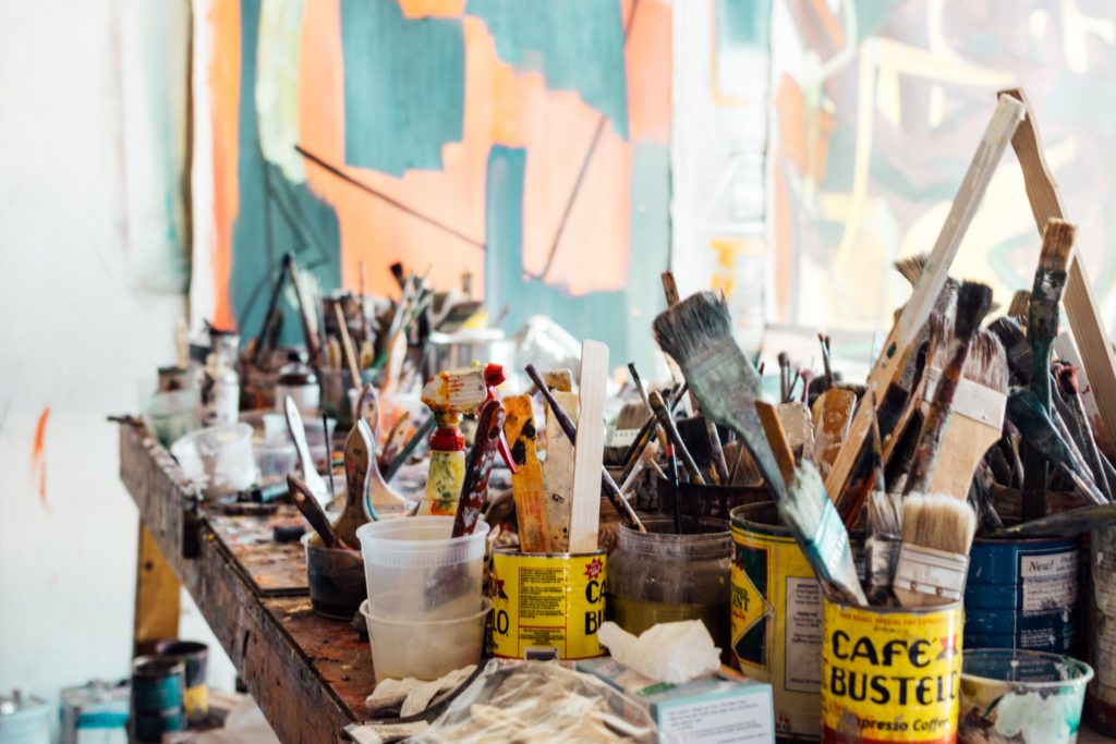 How to look at art: artist's studio table covered in containers filled with paint brushes.