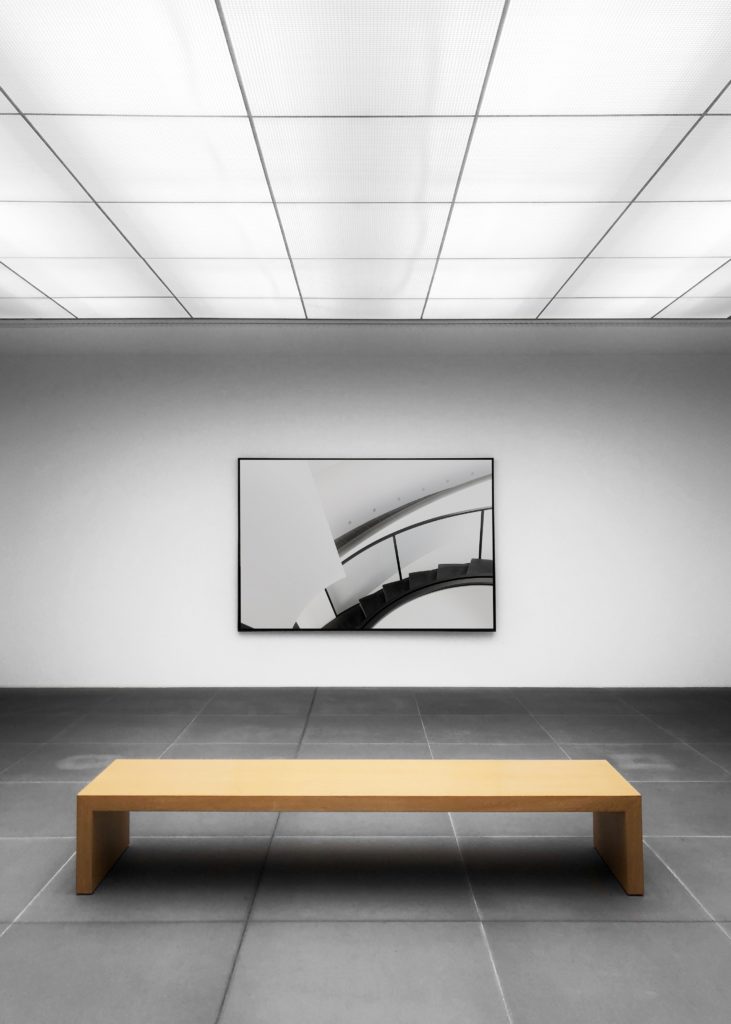 How to look at art: wooden bench in front of framed black and white photo of staircase.