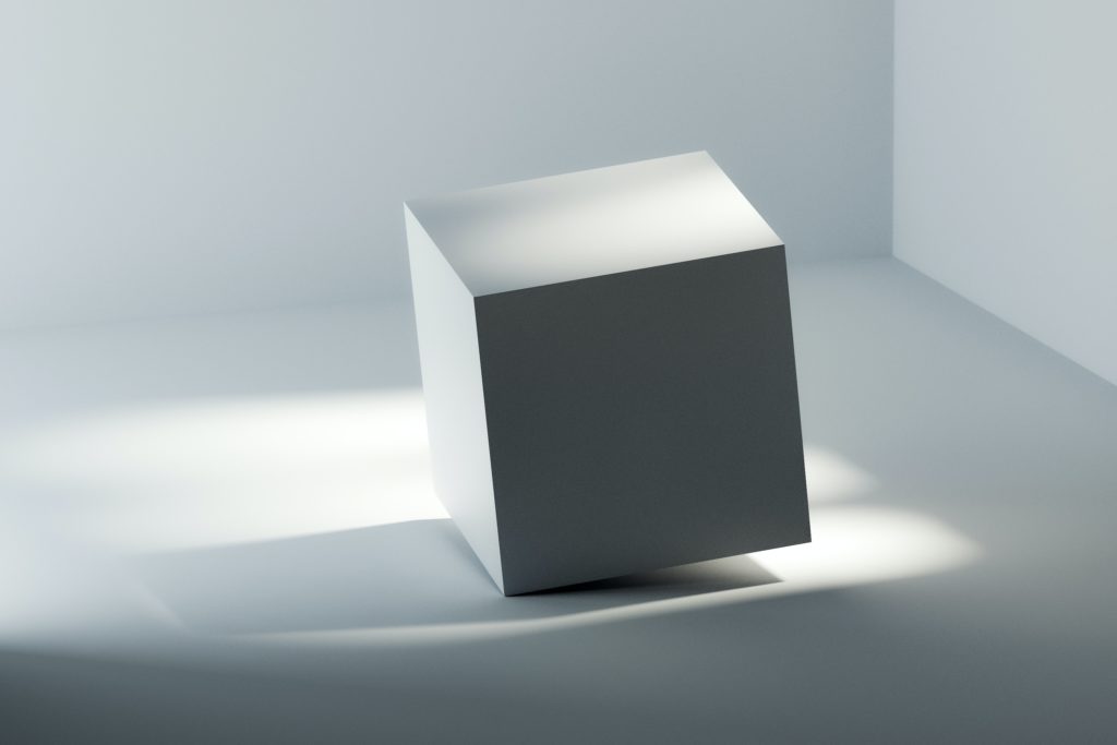 A white cube balanced on one corner in a white gallery.