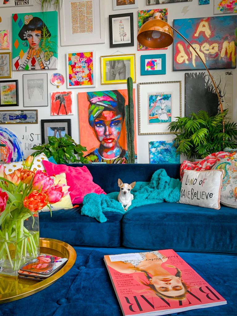 Minimalism and maximalism, part 1: colorful living room with cerulean velvet sofas and dozens of framed artworks displayed salon style.